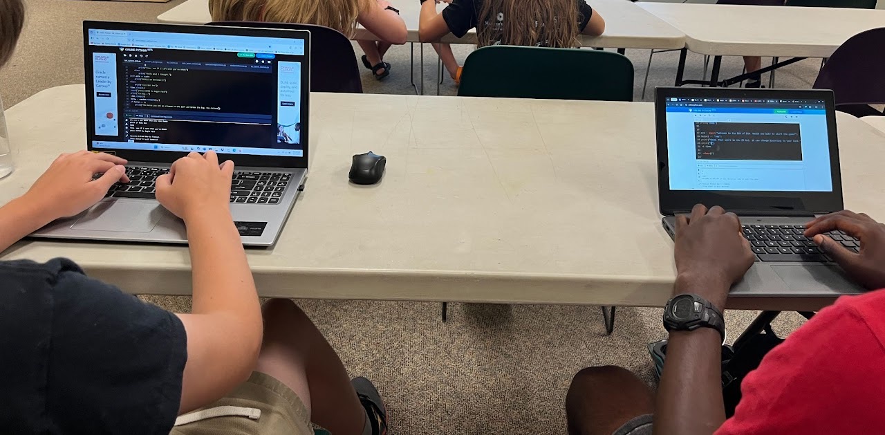 Students writing Python on laptops